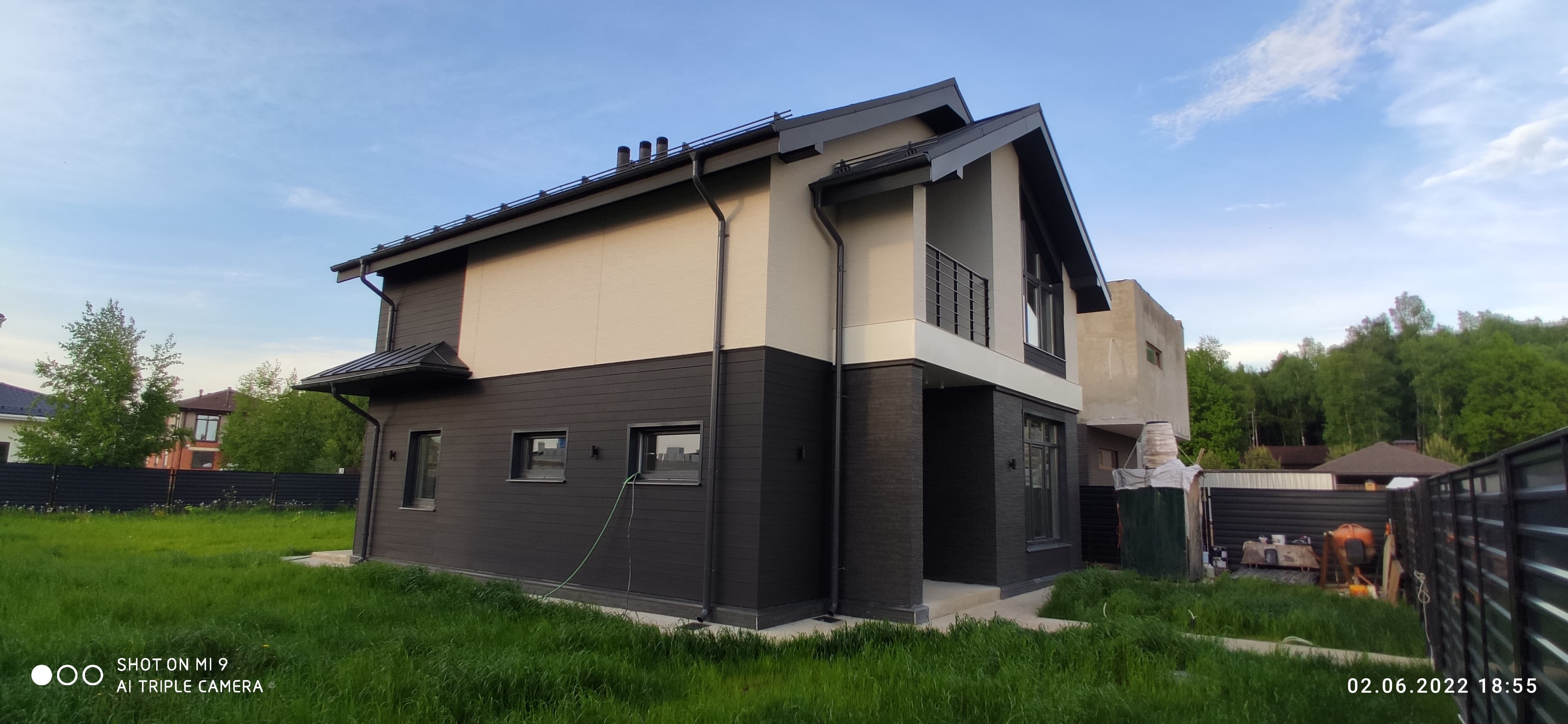 Дом ИЖС с тёмной облицовкой и зелёным газоном